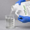 Alligare 2,4 D 1 gallon being poured into a graduated beaker for precise measurement before application.