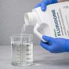 Alligare Fluridone being poured into a graduated beaker for precise measurement before application.