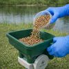Tan colored granules pouring into a hand spreader illustrating proper handling.