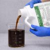 Cygnet Plus Spray Adjuvant 1 Gallon being poured into a graduated beaker for precise measurement before application.