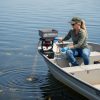 Female applicator applying brown colored granules to lake water via boat mounted spreader.