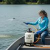 Female technician applying aquatic treatments to a lake with a 55 gallon boat mount Ironvale sprayer.