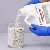 5 lb Flumigard WDG Aquatic Herbicide being poured into a graduated beaker for precise measurement before application.
