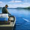 MAKO Concentrate Dye bottle visible during boat application on a larger pond.
