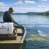 Technician applying treatments to a lake with a 55 gallon boat mount Ironvale sprayer
