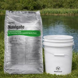 Navigate Granular Herbicide 50 lb bag next to a 5 gallon bucket by a pond