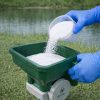 White colored granules pouring into a hand spreader illustrating proper handling.