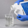 Sonar A.S gallon being poured into a graduated beaker for precise measurement before application.