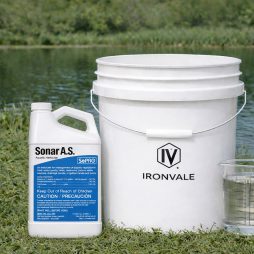 SePRO Sonar A.S. 1 gallon bottle beside a 5-gallon bucket and graduated measuring cup for size reference