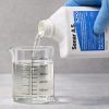 Sonar A.S being poured into a graduated beaker for precise measurement before application.