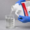 Weedtrine D being poured into a graduated beaker for precise measurement before application.